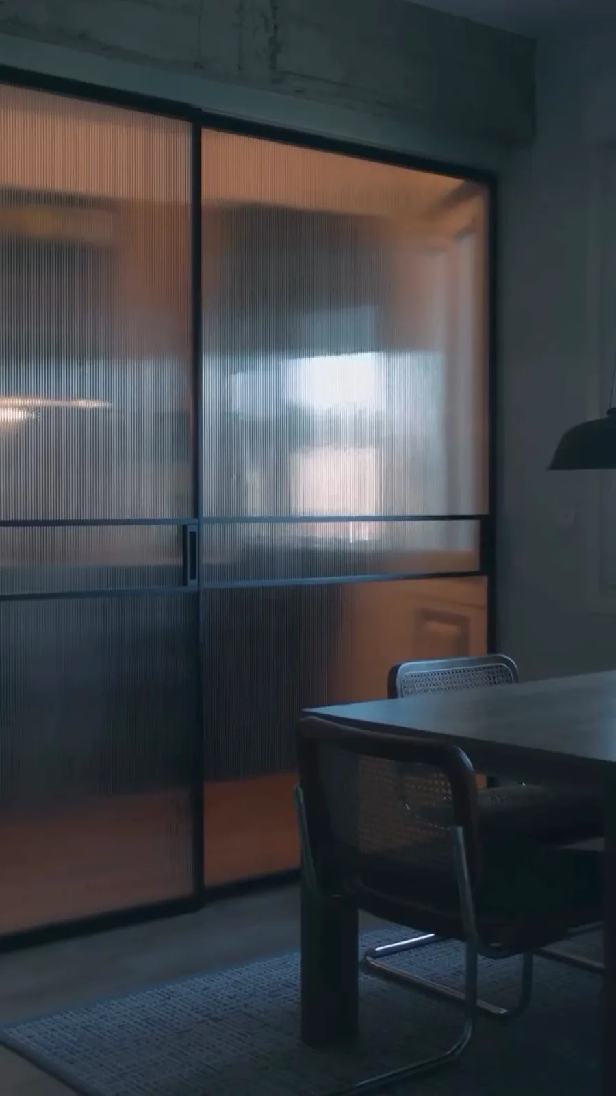 Atxuri · Casco Viejo de Bilbao: Dos puertas correderas de aluminio negro con cristal flutex para separar salón y cocina sin perder luz ni amplitud.